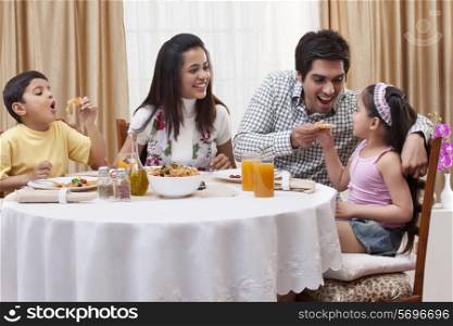 Family having fun while eating pizza together at restaurant