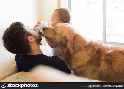 Family having fun with a feeding bottle - Father, baby and dog!