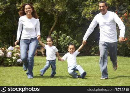 family having fun with parents and their two kids running outdoors