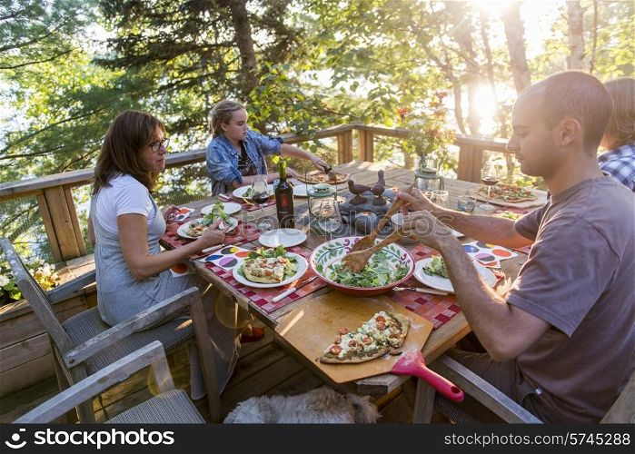 Family having meal on a deck, Lake of The Woods, Ontario, Canada