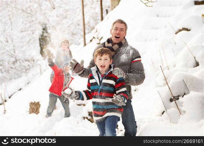 Family Having Snowball Fight In Snowy Landscape