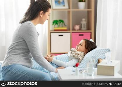 family, health and people concept - mother and sick little daughter lying in bed at home. mother and sick little daughter in bed at home