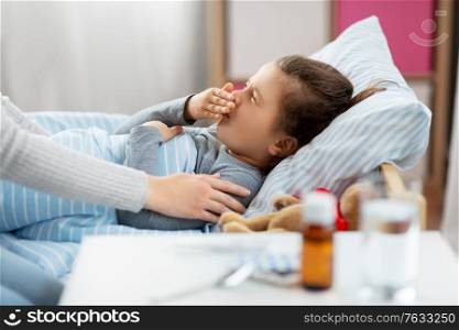 family, health and people concept - mother and sick little daughter lying in bed at home. mother and sick little daughter in bed at home