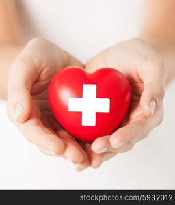 family health, charity and medicine concept - female hands holding red heart with cross sign