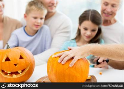 family, helloween, generation, holidays and people concept - happy family making jack-o-lantern of pumpkins at home