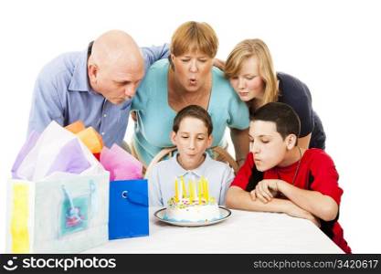 Family helps a little boy blow out his birthday candles. White background.