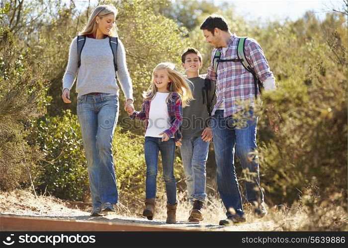 Family Hiking In Countryside Wearing Backpacks