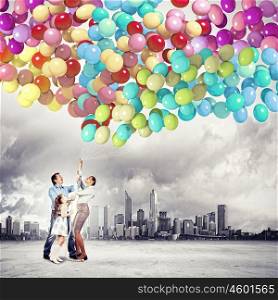 Family holding colorful balloons. Image of happy family holding bunch of colorful balloons
