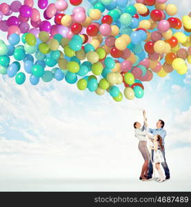 Family holding colorful balloons. Image of happy family holding bunch of colorful balloons