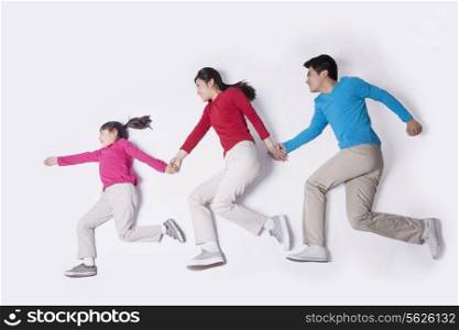 Family holding hands and imitating running, studio shot