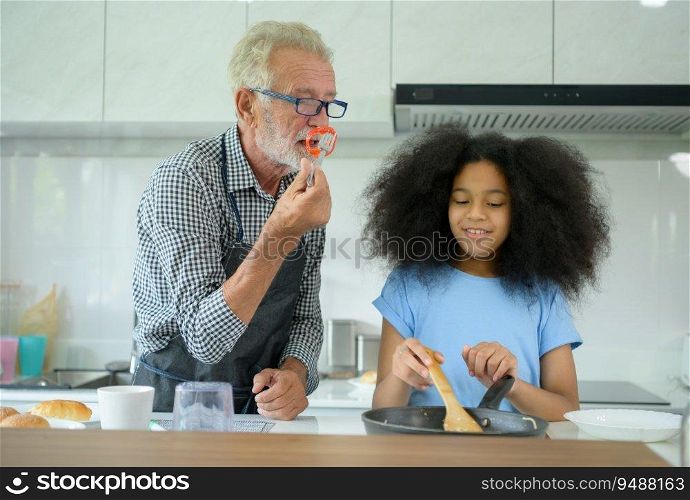 Family holiday activities with grandfather and grandchildren. Cooking dinner together for the family Grandfather is teaching cooking to his half-Asian granddaughter African American