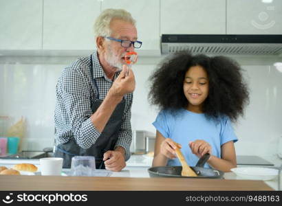 Family holiday activities with grandfather and grandchildren. Cooking dinner together for the family Grandfather is teaching cooking to his half-Asian granddaughter African American