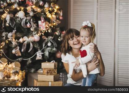 Family holiday joyful mood.. Happy mother and daughter playing on the background of Christmas green trees 7250.