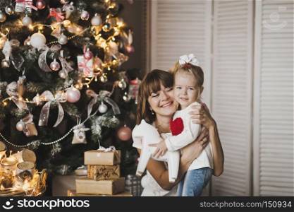 Family holiday joyful mood.. Happy mother and daughter playing on the background of Christmas green trees 7251.