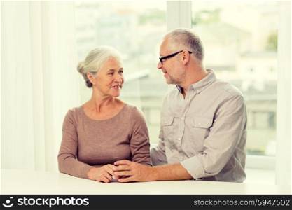 family, holidays, age and people concept - happy senior couple sitting on sofa at home