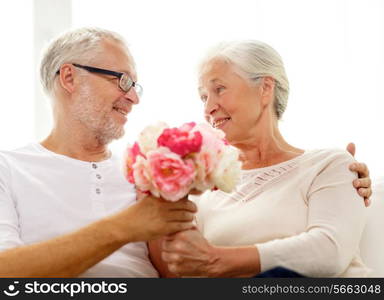 family, holidays, age and people concept - happy senior couple with bunch of flowers at home