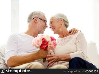family, holidays, age and people concept - happy senior couple with bunch of flowers at home