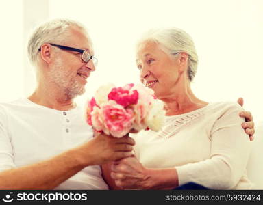 family, holidays, age and people concept - happy senior couple with bunch of flowers at home