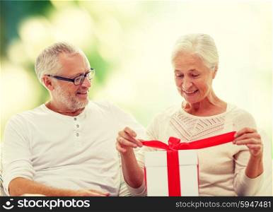 family, holidays, age and people concept - happy senior couple with gift box over green background