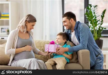 family, holidays and greetings concept - father and little son giving present to happy pregnant mother at home. family giving present to pregnant mother at home