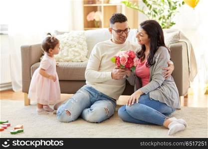 family, holidays and greetings concept - happy husband giving flowers to his wife at home. happy husband giving flowers to his wife at home. happy husband giving flowers to his wife at home