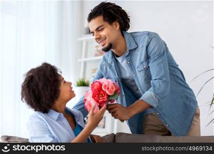 family, holidays and people concept - happy couple with bunch of flowers at home. happy couple with bunch of flowers at home