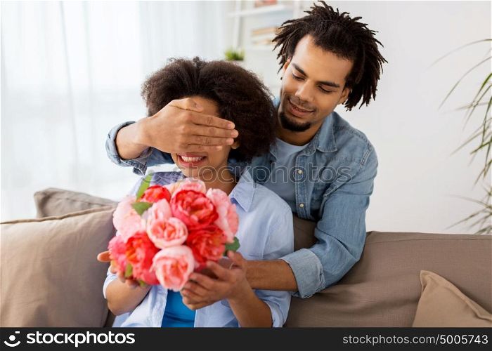 family, holidays and people concept - happy couple with bunch of flowers at home. happy couple with bunch of flowers at home