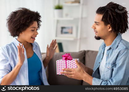 family, holidays and people concept - happy couple with gift box at home. happy couple with gift box at home