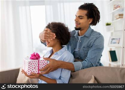 family, holidays and people concept - happy couple with gift box at home. happy couple with gift box at home