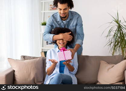 family, holidays and people concept - happy couple with gift box at home. happy couple with gift box at home