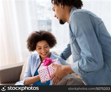 family, holidays and people concept - happy couple with gift box at home. happy couple with gift box at home