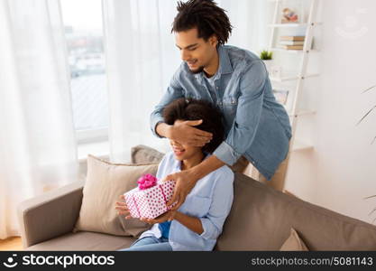 family, holidays and people concept - happy couple with gift box at home. happy couple with gift box at home