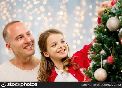family, holidays and people concept - happy father and daughter decorating christmas tree over lights background. father and daughter decorating christmas tree