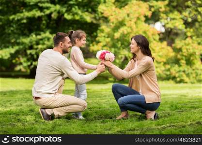 family, holidays and people concept - happy father and little girl giving flowers to mother in summer park