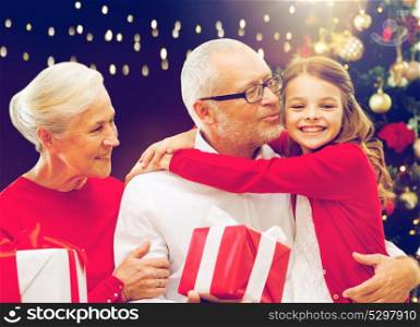 family, holidays and people concept - happy grandparents and granddaughter with gift boxes and christmas thee over lights background. happy family with christmas gifts