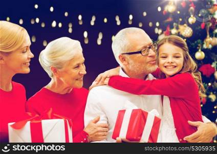 family, holidays and people concept - happy grandparents, granddaughter and mother with gift boxes and christmas thee over lights background. happy family with christmas gifts