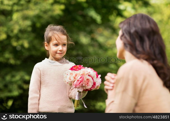 family, holidays and people concept - happy little girl giving flowers to mother in summer park