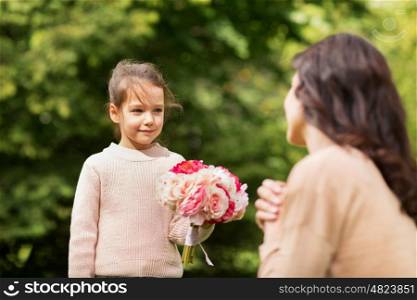 family, holidays and people concept - happy little girl giving flowers to mother in summer park