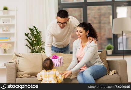 family, holidays and people concept - happy mother, father and baby daughter with birthday present at home. happy family with birthday present at home