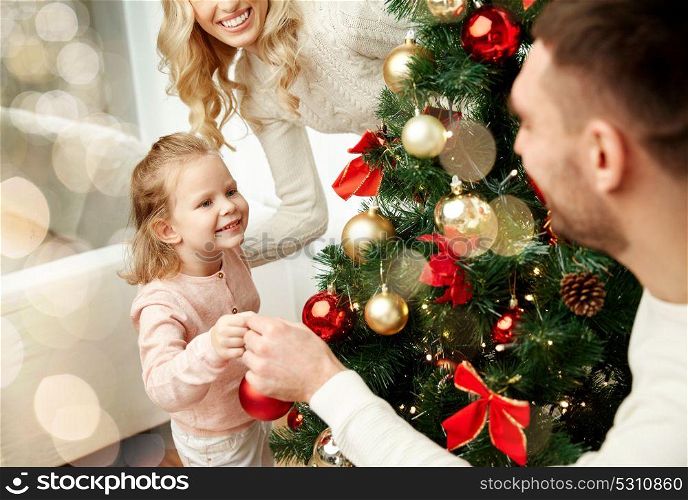 family, holidays and people concept - happy mother, father and little daughter decorating christmas tree over lights background. happy family decorating christmas tree