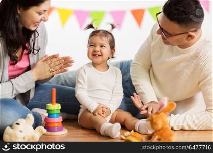 family, holidays and people concept - happy mother, father and little daughter clapping hands on birthday party. baby girl with parents clapping hands. baby girl with parents clapping hands