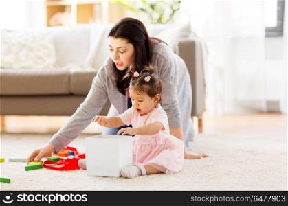 family, holidays and people concept - mother and happy little daughter playing with toy or gift box at home. baby girl playing with toy or gift box at home. baby girl playing with toy or gift box at home