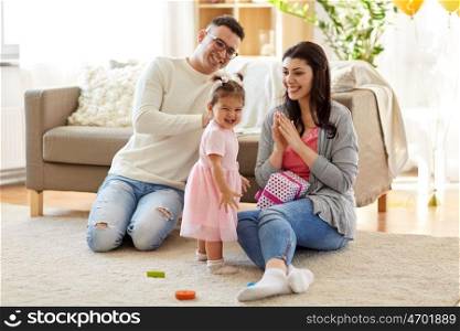 family, holidays and people concept - mother, father and happy little daughter with gift box at home birthday party. baby girl with birthday gift and parents at home. baby girl with birthday gift and parents at home