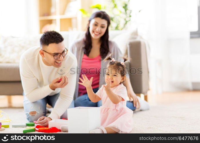 family, holidays and people concept - mother, father and happy little daughter with gift box at home birthday party. baby girl with birthday gift and parents at home . baby girl with birthday gift and parents at home