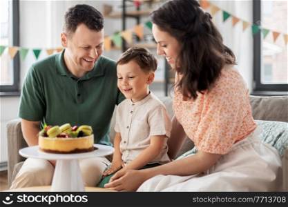 family, holidays and people concept - portrait of happy mother, father and little son with birthday cake at home party. happy family with birthday cake at home