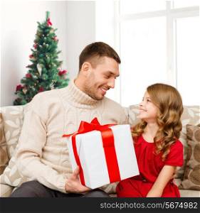 family, holidays and people concept -smiling father and daughter with gift box over living room and christmas tree background