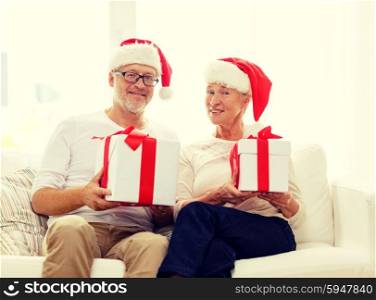 family, holidays, christmas, age and people concept - happy senior couple in santa helper hats with gift boxes at home