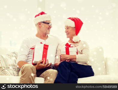 family, holidays, christmas, age and people concept - happy senior couple in santa helper hats with gift boxes at home