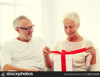 family, holidays, christmas, age and people concept - happy senior couple with gift box over white room background