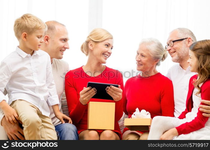 family, holidays, christmas, technology and people concept - smiling family with gift box and tablet pc computer sitting on couch at home